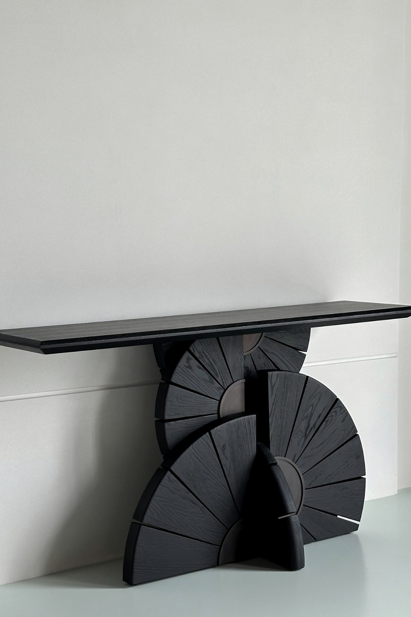 A carved black fan console in a pale room